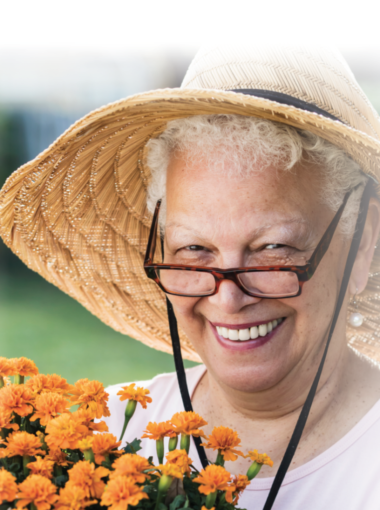 Senior woman with glasses and hat holding marigold plans