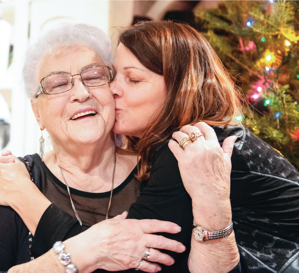 Grandma gets a hug at a wreath making event from her daughter