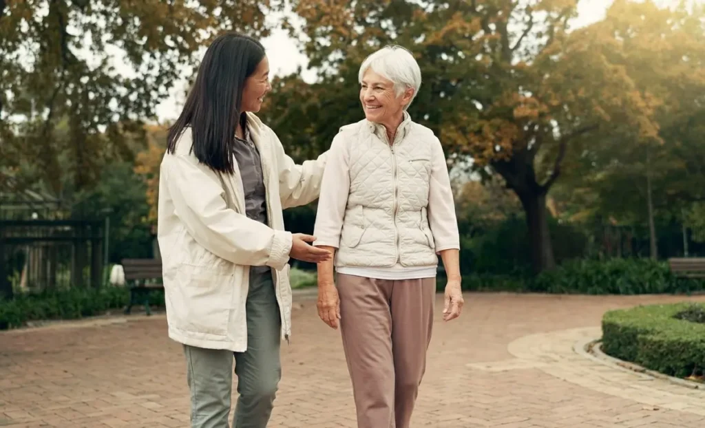Senior and caregiver share a warm moment while walking